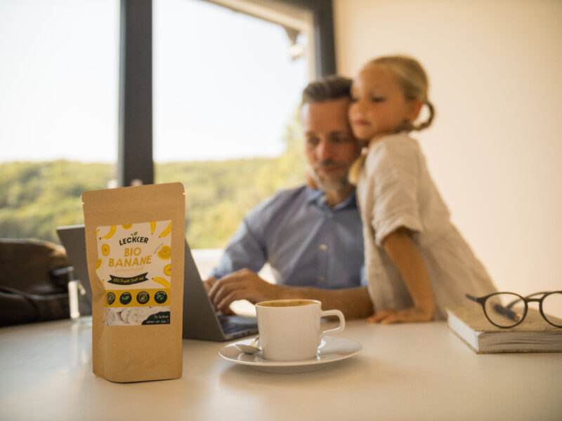 Ein Mann arbeitet neben seiner Tochter und gefriergetrockneten Bananen